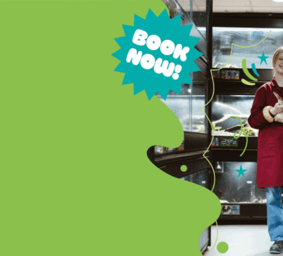 Image of smiling student standing in Reptile room holding a snake, promoting Brinsbury College Open Events.