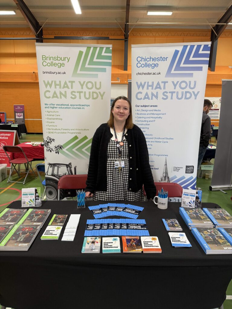 Sophie Holbourne standing in front of a Brinsbury college information desk